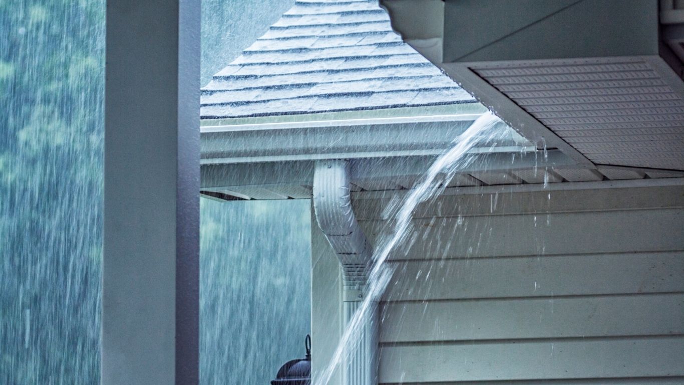 Rainwater overflowing from gutters during heavy runoff requiring gutter replacement.