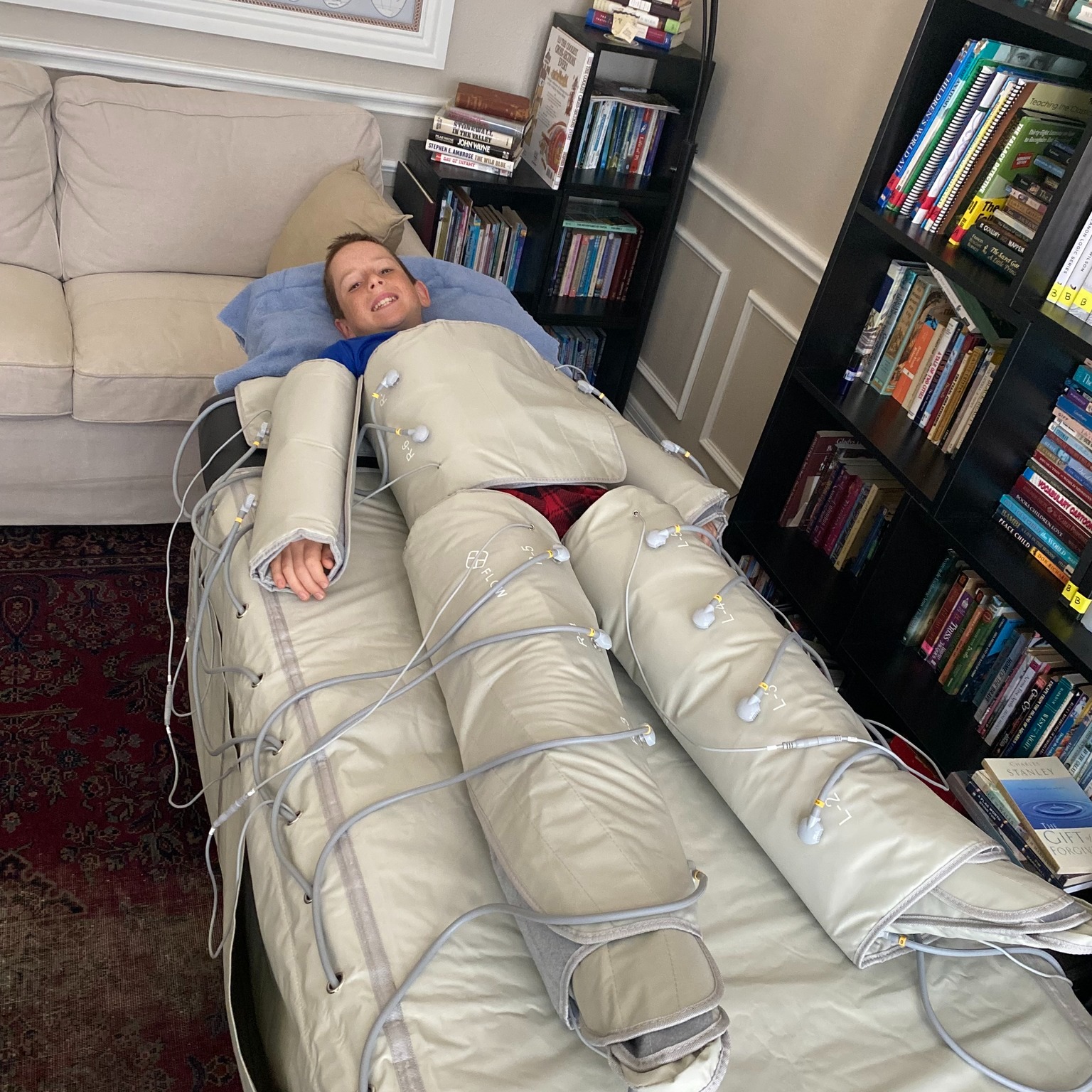 A smiling boy laying down in the Lymph30 from torso to toe.