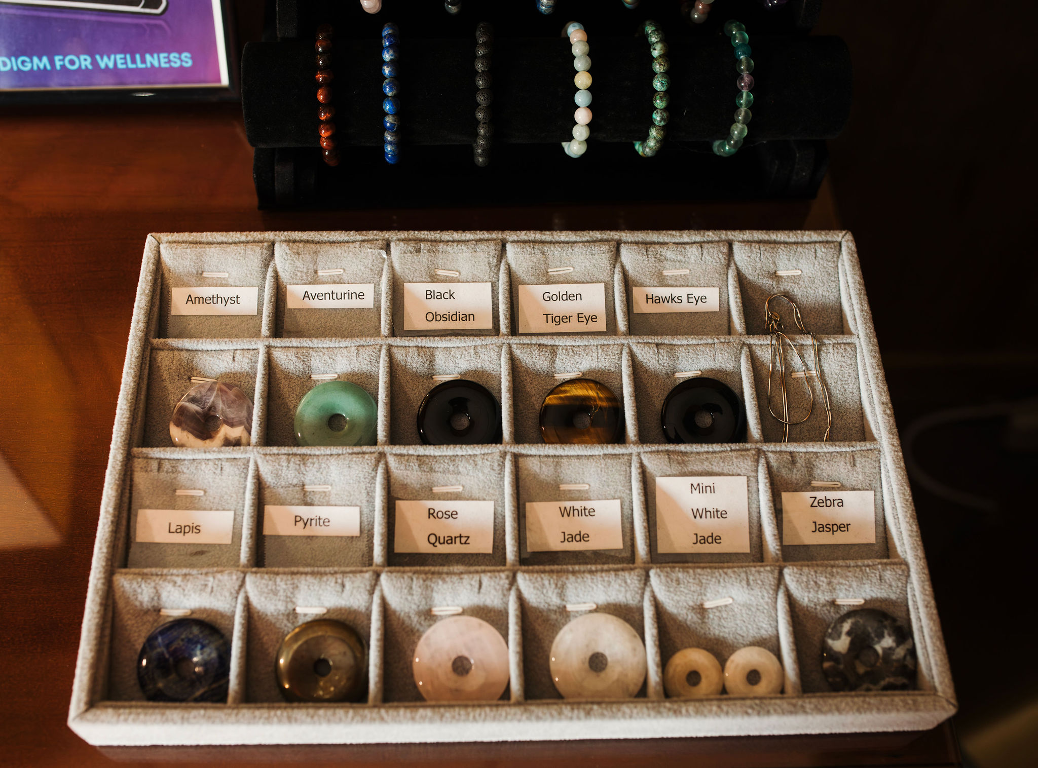 A grey tray of various types of crystal medallions and bracelets.
