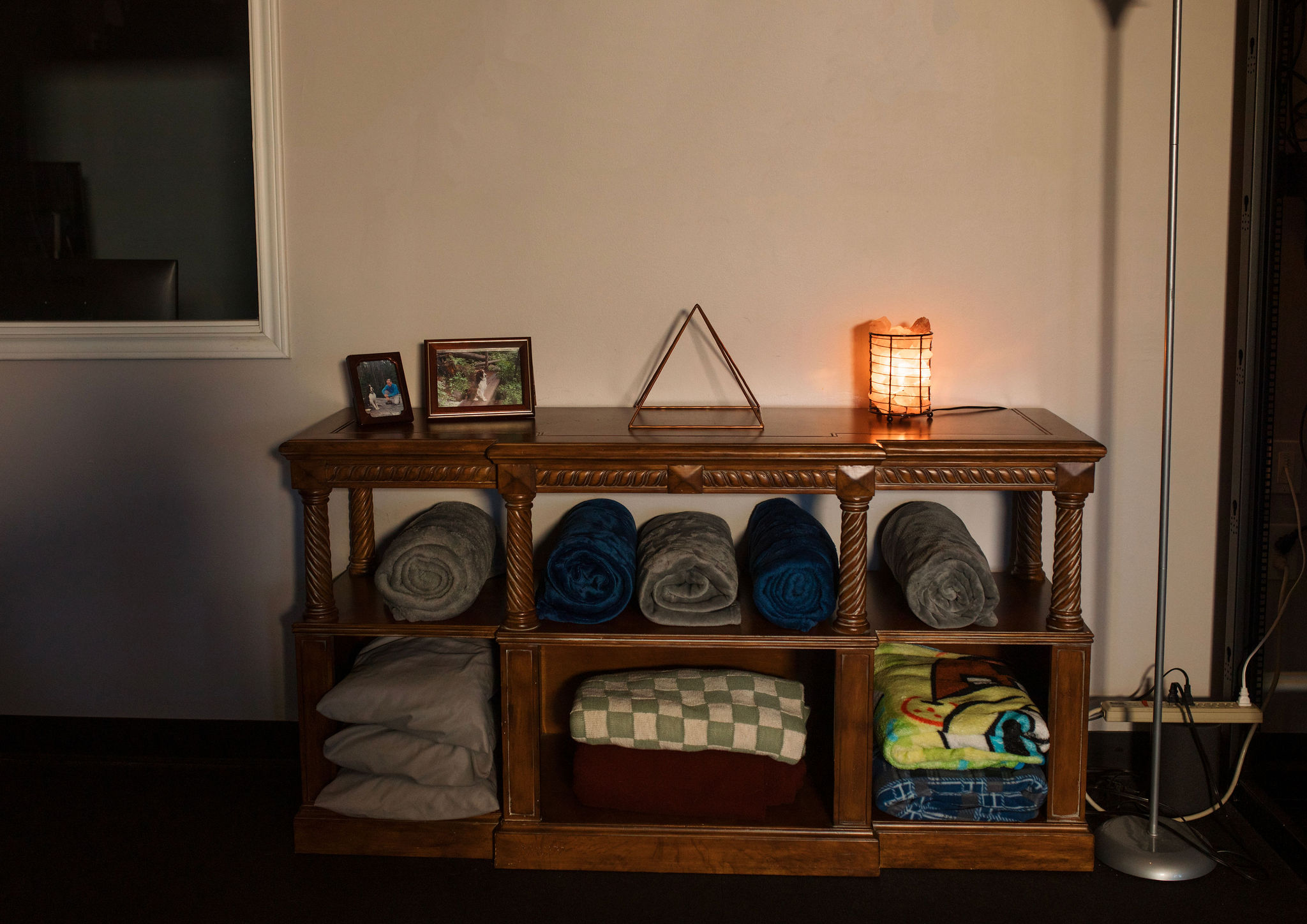 A wood shelving unit in the Energy Lounge at SEWC that stores comfort items and an energy enhancing copper pyramid.