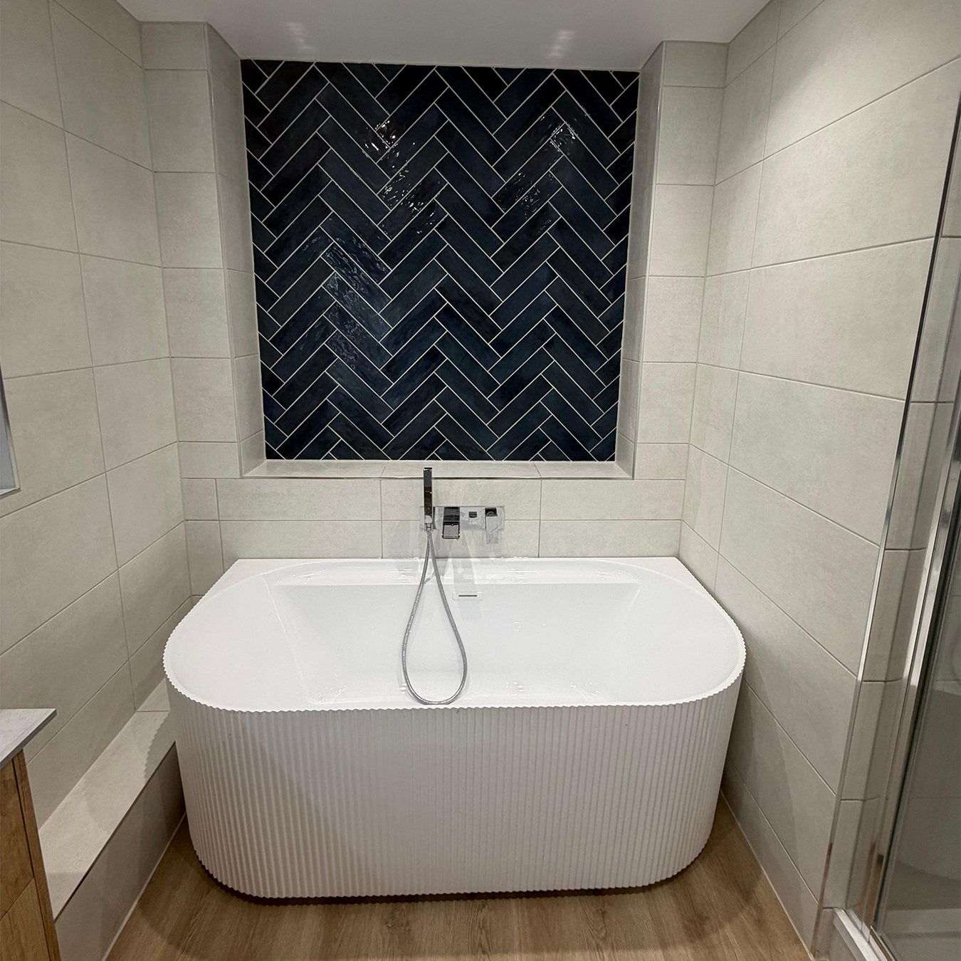 Bathroom with herringbone tile feature wall and freestanding bath