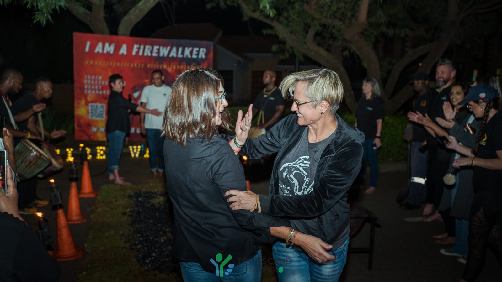 Two firewalkers celebrate with an embrace after crossing the coals