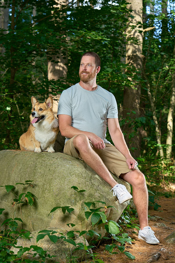 Gronk the Pembroke Welsh Corgi with his dad sitting on a rock in the woods in Stow, MA
