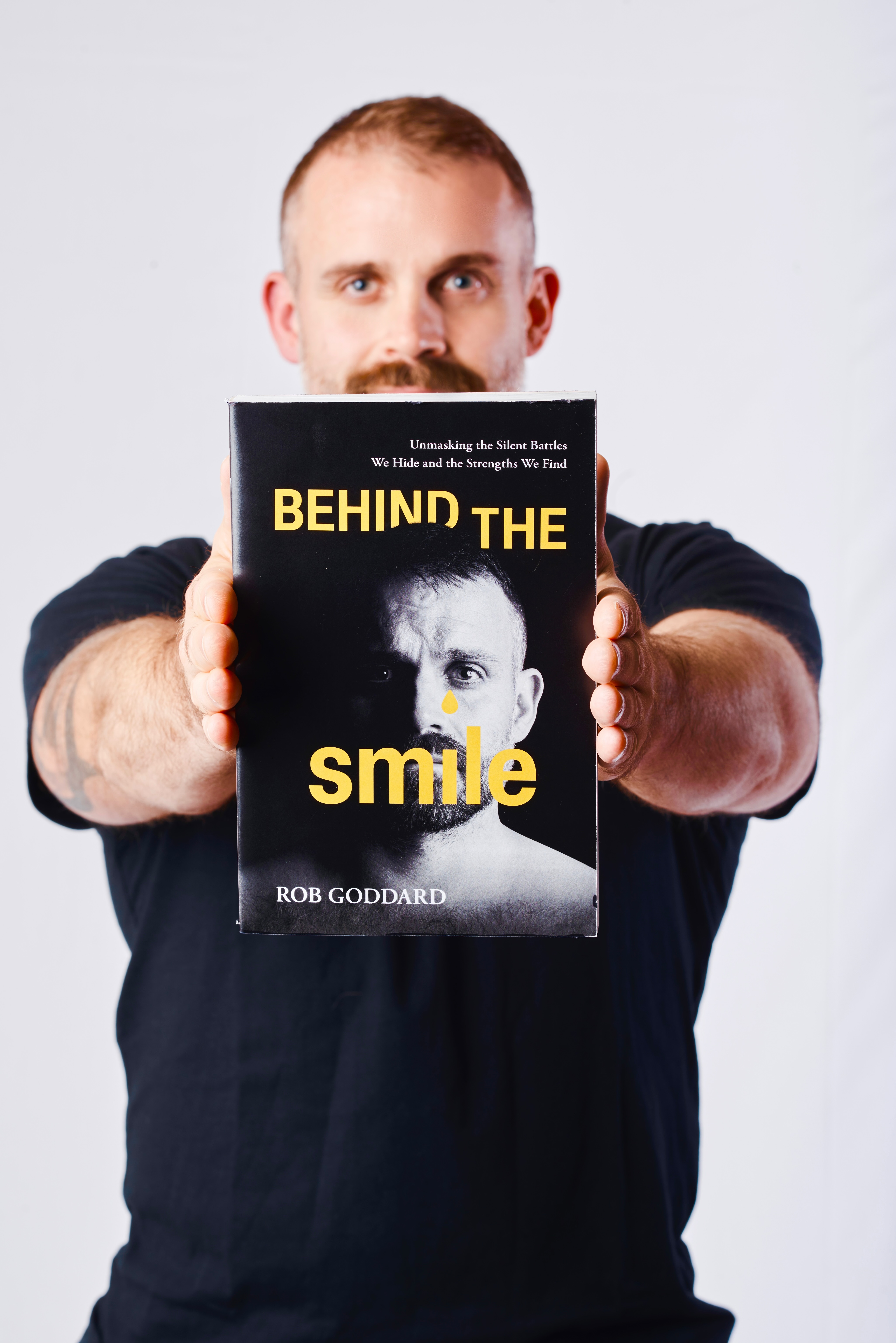 Rob Goddard holding his book, Behind the Smile