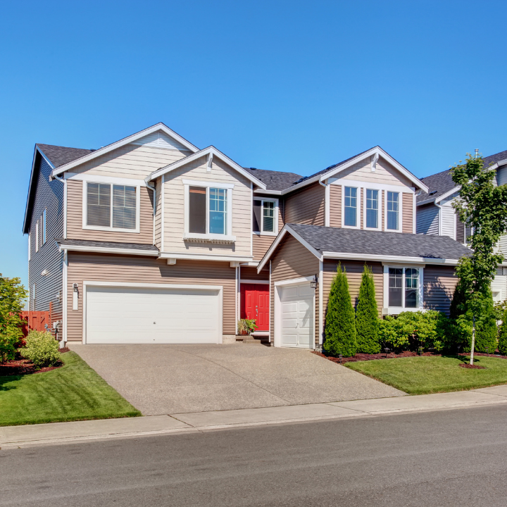 A spacious two-story suburban home with a vibrant red door and well-maintained exterior, perfect for family living.