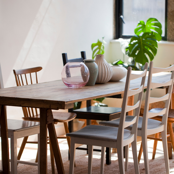 Beautiful dining area with a rustic wooden table, unique vases, and lush green plants, creating a warm and inviting space.