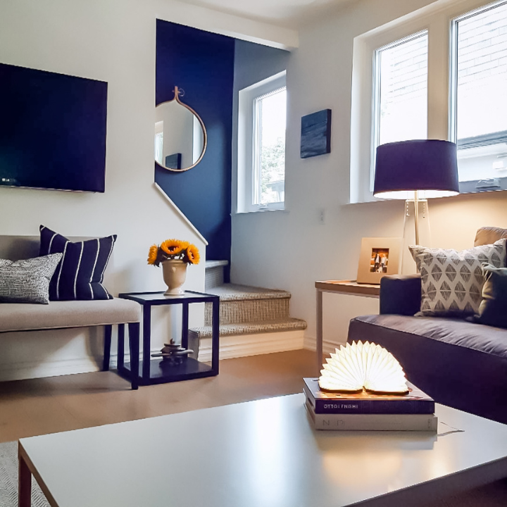 Bright and cozy living room with modern decor, featuring a vase of sunflowers and natural light streaming through large windows.