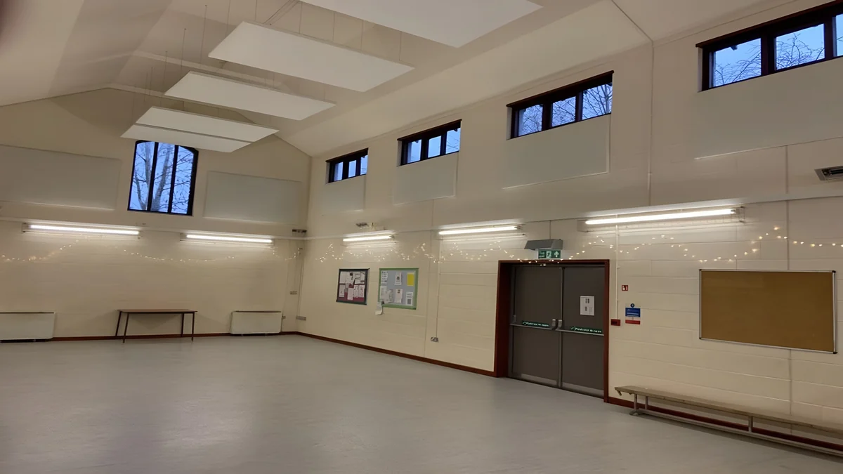 White suspended acoustic ceiling panels in Storth Heron Hall, above an open hall with high windows.