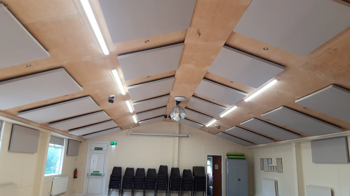 Grey acoustic panels between the ceiling beams and on the upper walls at Askwith Village Hall.