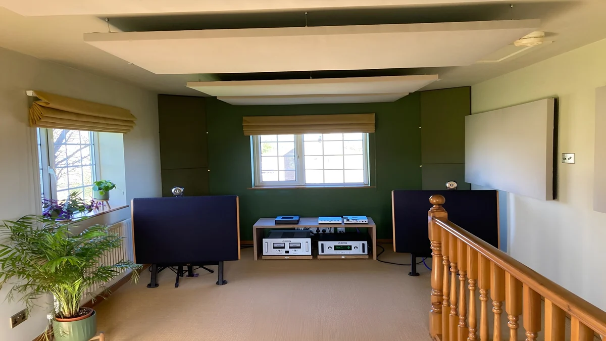 White suspended acoustic panels and wall treatment above a home music system in a green-walled room.