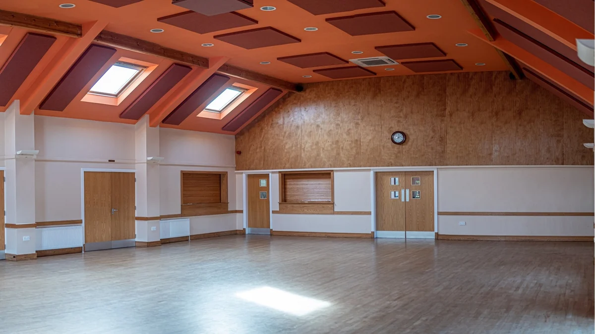 Acoustic panels on the sloping ceiling and walls of Little Wenlock Village Hall, with exposed timber beams.