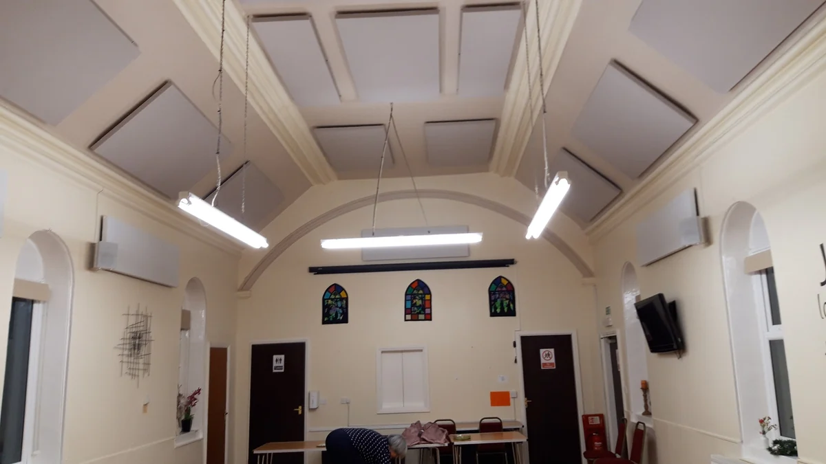 Rectangular acoustic panels fitted to the sloping ceiling of Eggborough Methodist Church, with arched windows.
