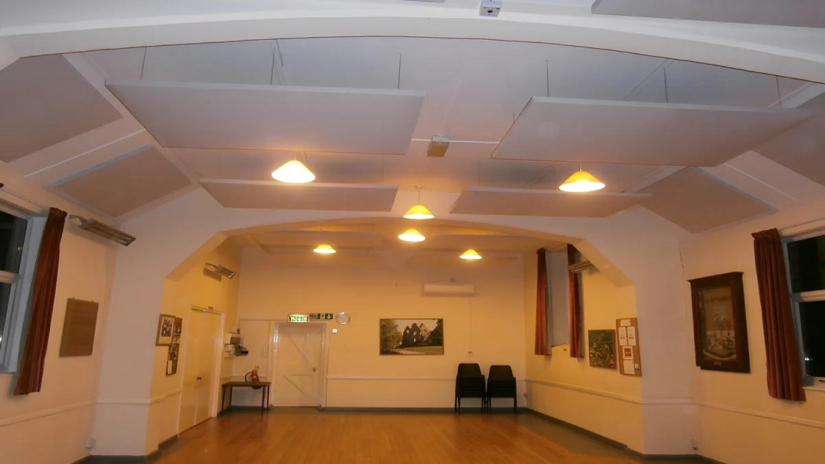 White suspended acoustic panels beneath the vaulted ceiling at Kilve Village Hall.