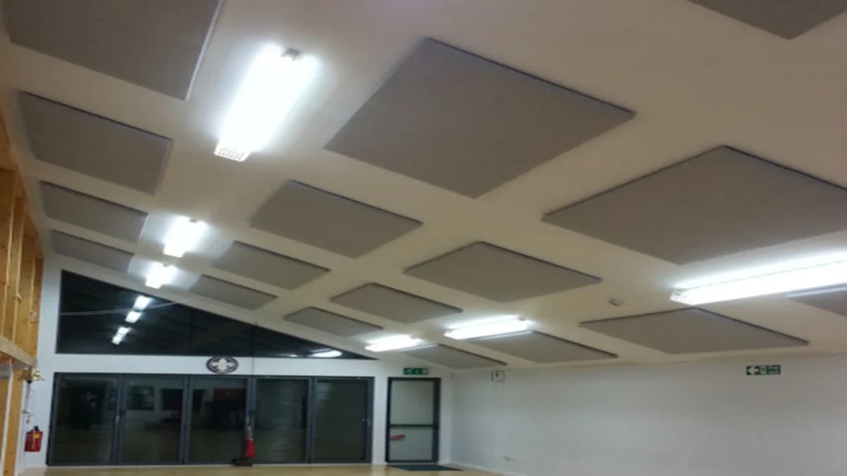 Grey rectangular acoustic panels on the ceiling of a scout hut, between strip lights.