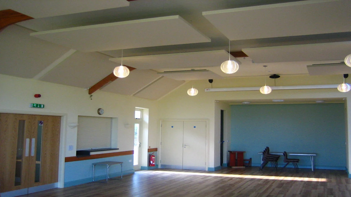 White suspended acoustic ceiling panels above the wooden floor and blue-grey walls of Ryton Village Hall.