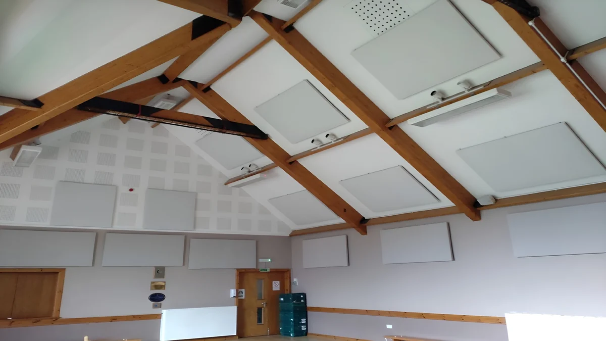 White acoustic ceiling and wall panels around exposed timber beams at Westruther Village Hall.