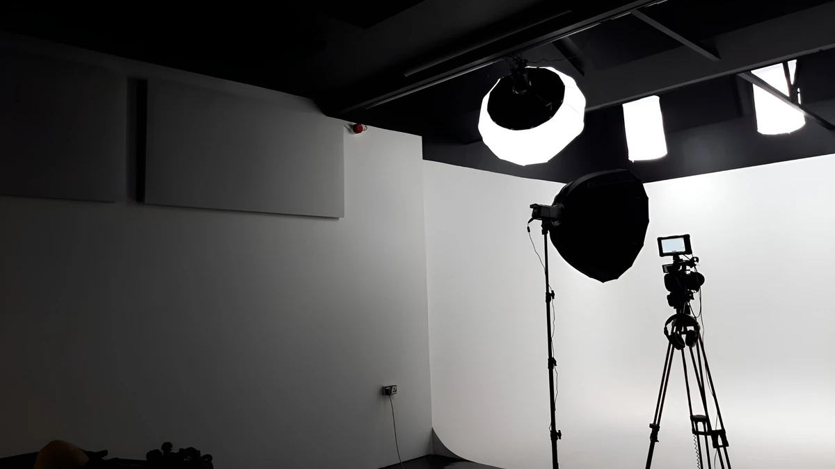 Grey wall-mounted acoustic panels beside a white studio backdrop, camera and lighting equipment in Giant Leap Productions studio 2.