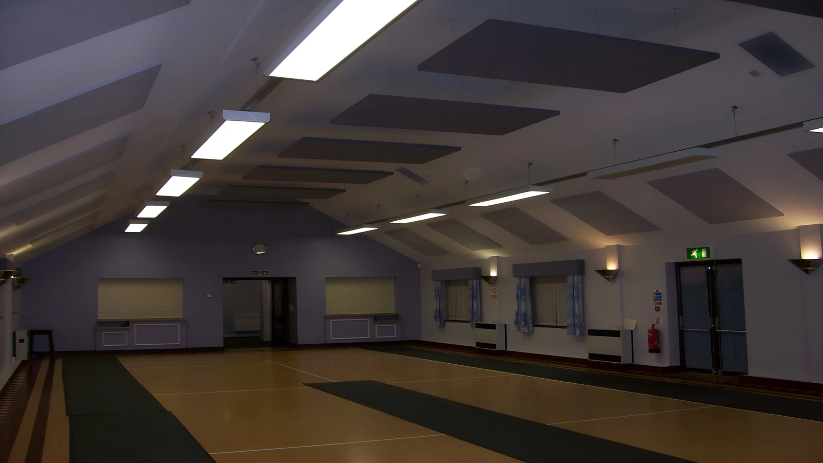 Grey acoustic ceiling panels above a marked hall floor, with matching wall panels at Norwell Village Hall.