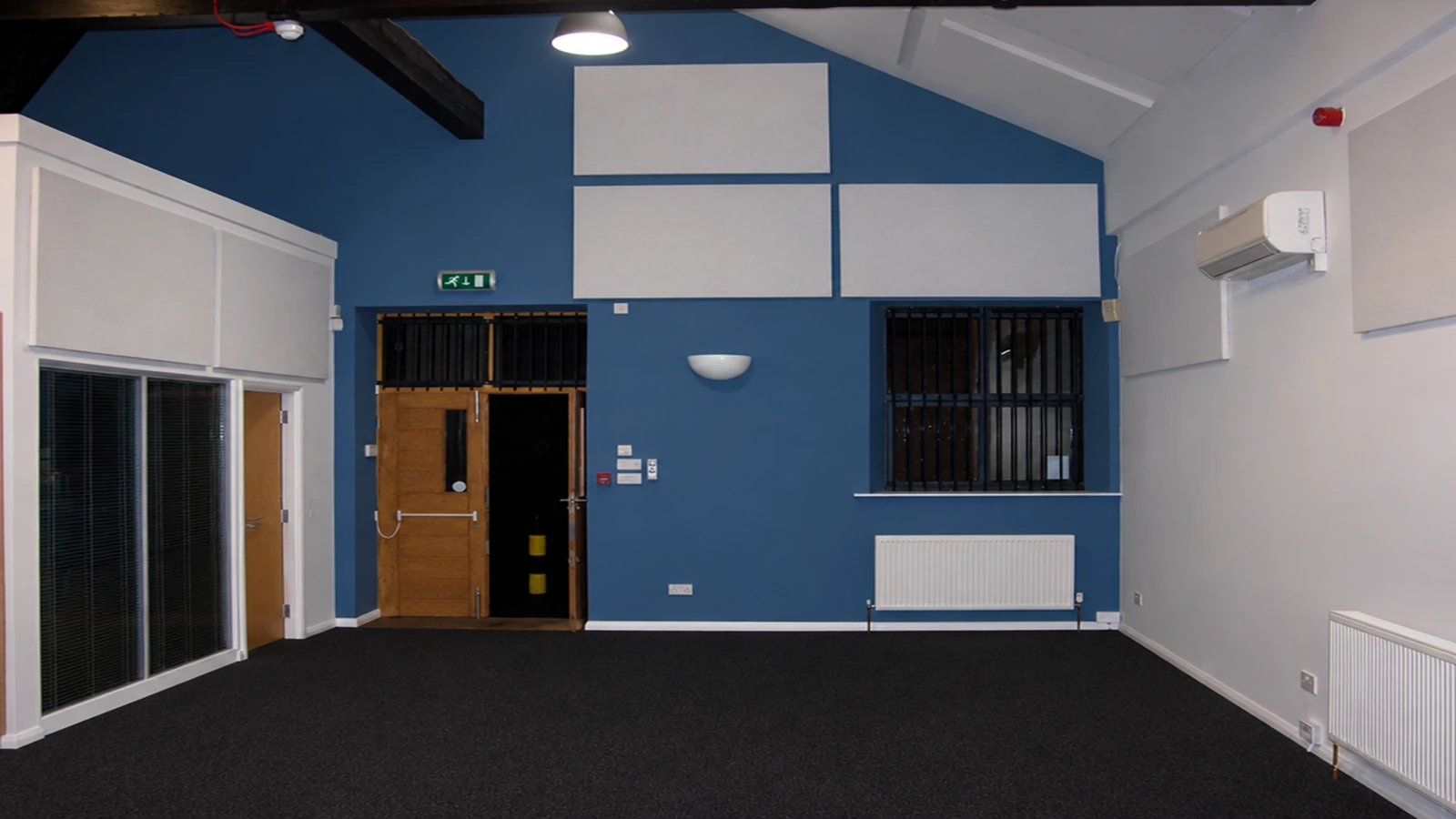 White acoustic panels on blue and white walls beneath exposed beams at Mercury Quays office suites.