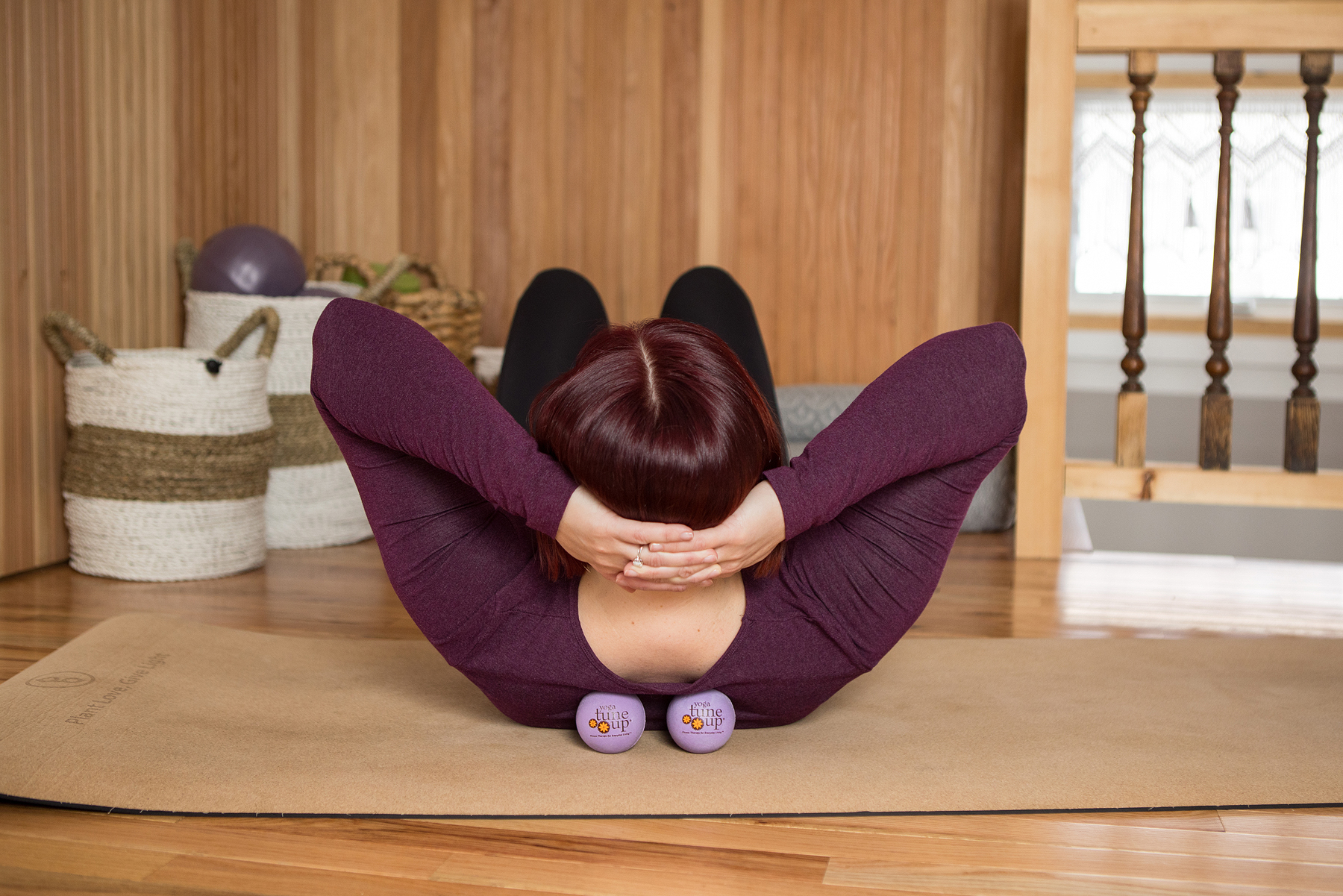 Ashley lying on her back with massage therapy balls under her shoulders.