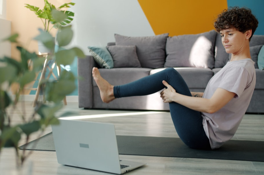 Woman in seated meditation pose in front of her laptop. 