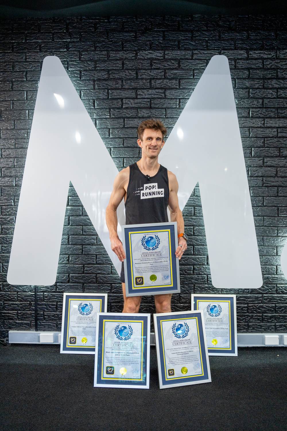 Sam Stow holding his framed endurance record certificates