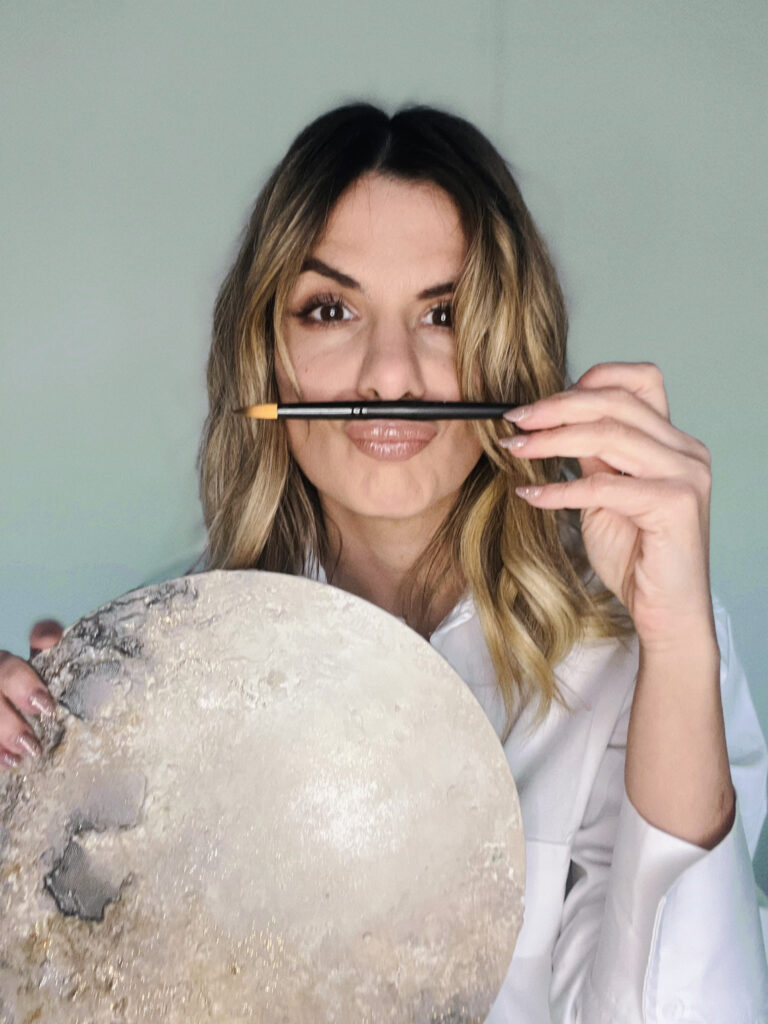 Maikai Polo en su estudio sosteniendo una luna pintada a mano