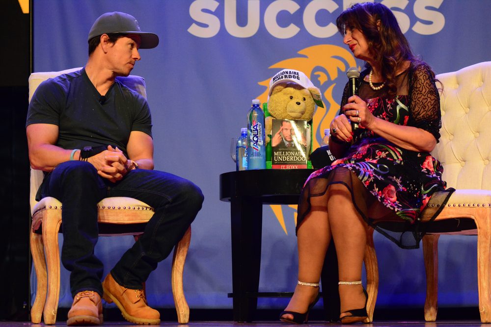 Dr. Dalal Akoury interviews actor Mark Wahlberg on stage at an industry event