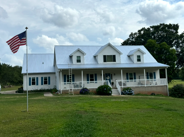 Cape-style home with finished metal roof and American flag