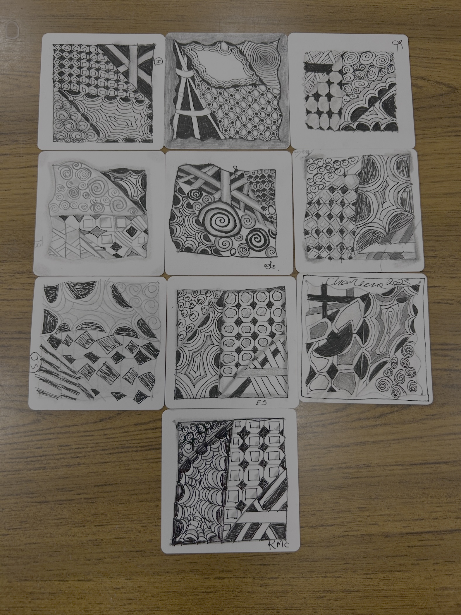 A collection of tiles gathered on a desk that were drawn by students in their first-ever Zentangle session. A collection of tiles gathered on a desk that were drawn by students in their first-ever Zentangle session.