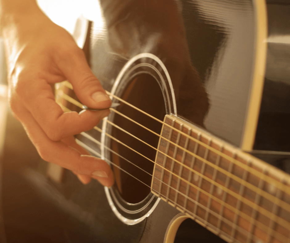 A close-up on an acoustic guitar. Someone is playing it.