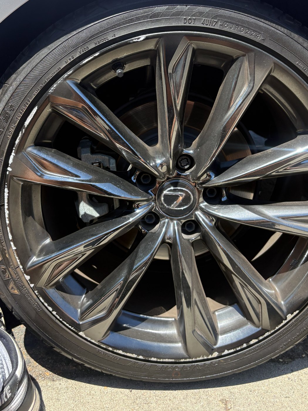 Curb rash along the lip of a dark multi-spoke Lexus alloy wheel, before refinishing