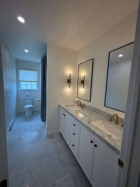 Bathroom remodel featuring a double vanity with white shaker cabinets, marble in Reading, PA by JB Plumbing HVAC & Constru...