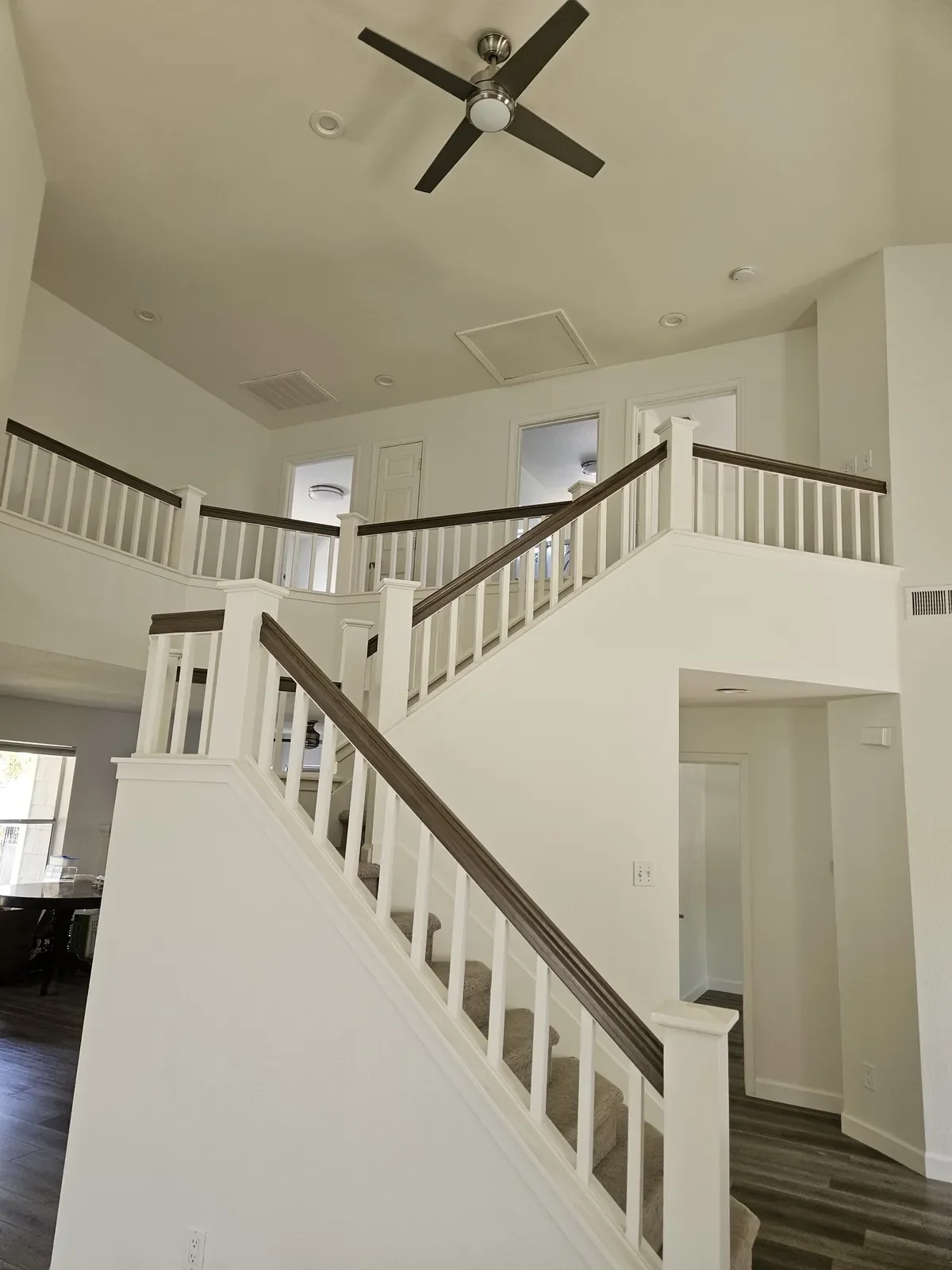 Two-story staircase and loft with freshly painted white walls and balusters
