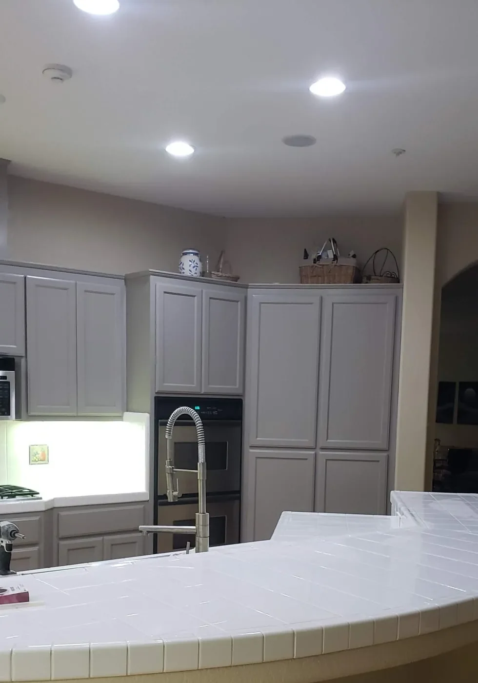 Kitchen with cabinets painted soft gray and a curved tile island