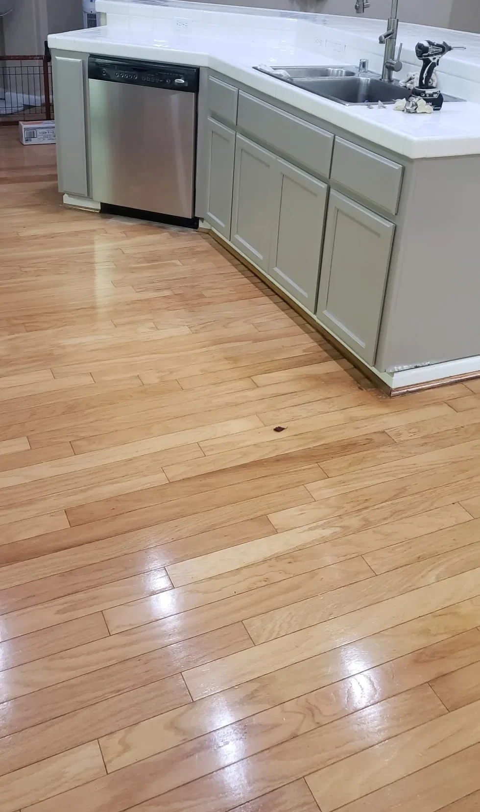 Lower kitchen cabinets painted warm gray beside a hardwood floor