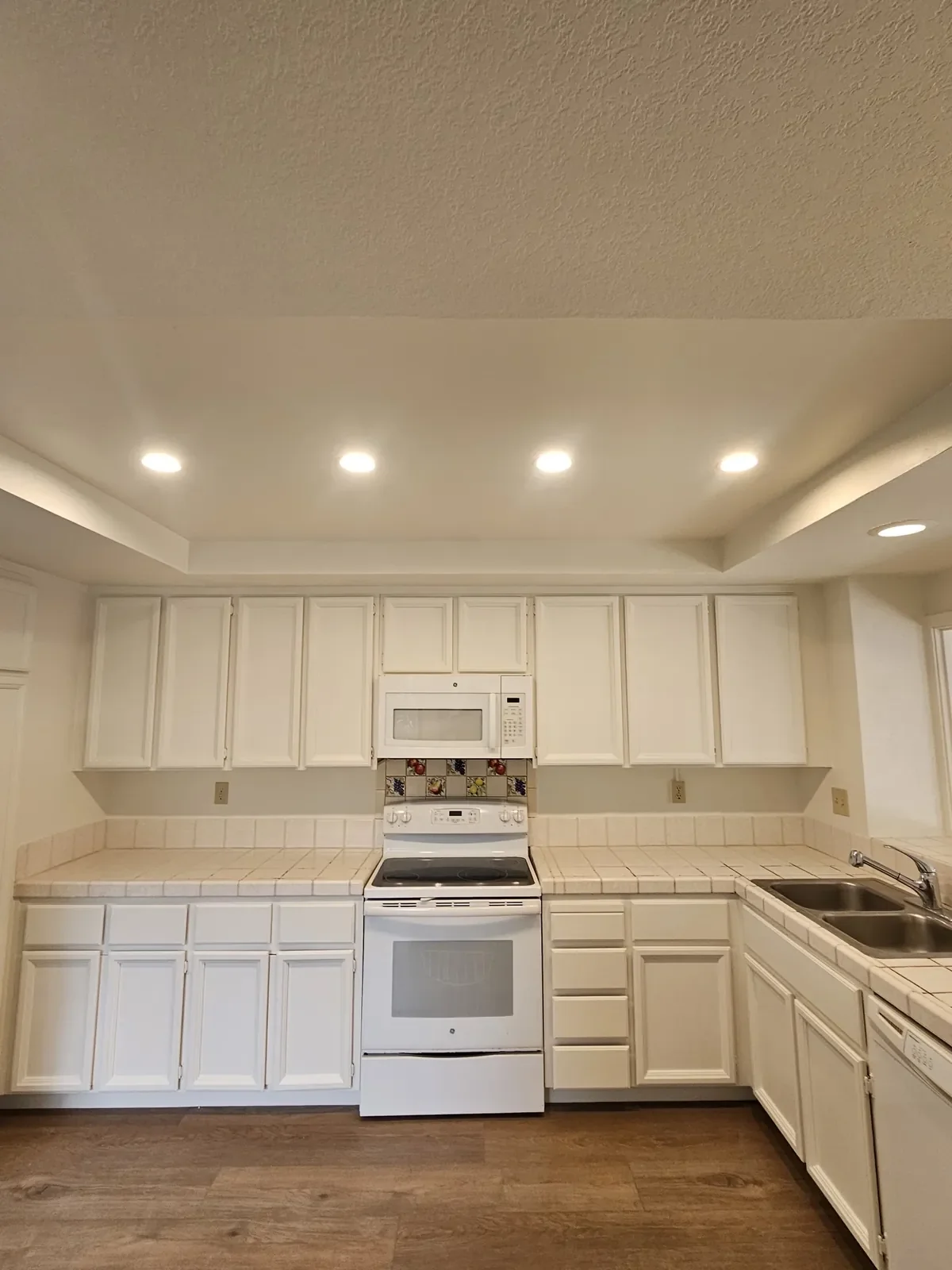 Kitchen cabinets painted white under a tray ceiling