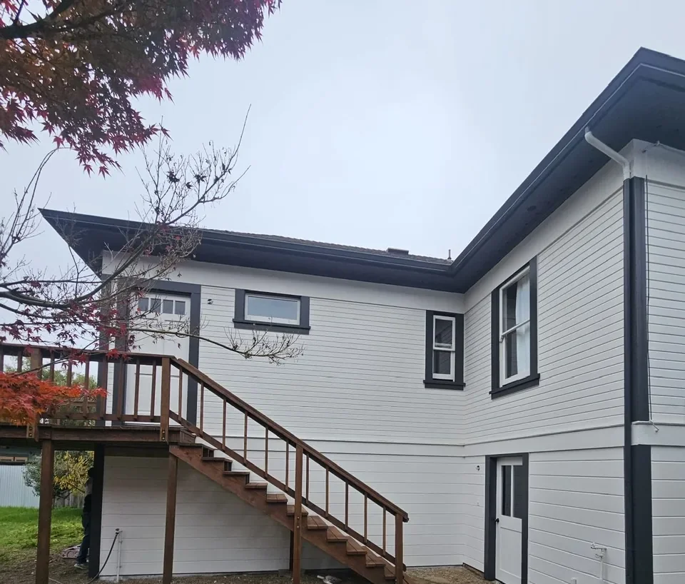 White siding with black trim and stained wood stairs