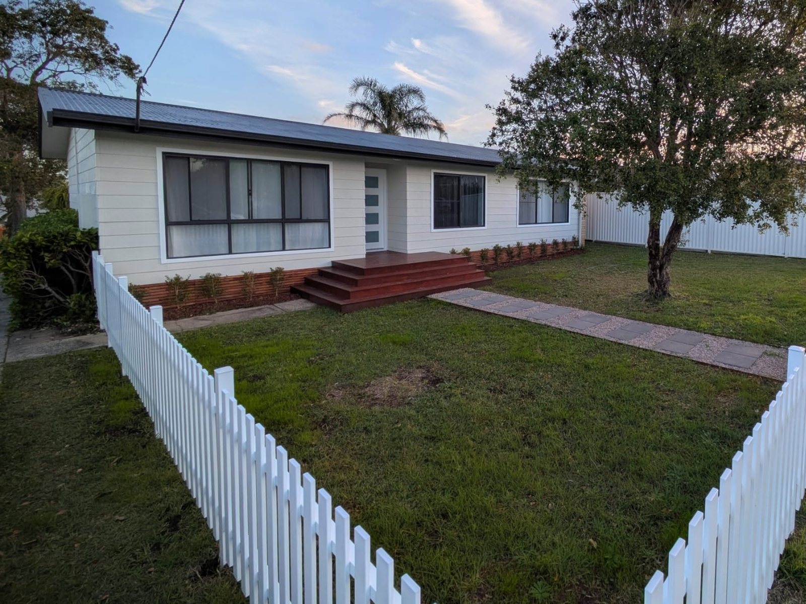 The second house after: new cladding paint, deck, picket fence