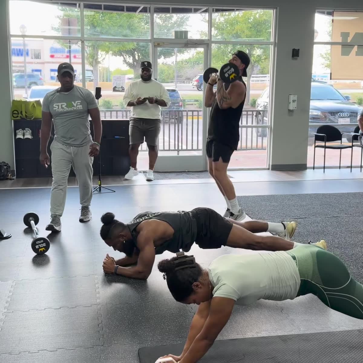 Two members holding plank while others train behind them.