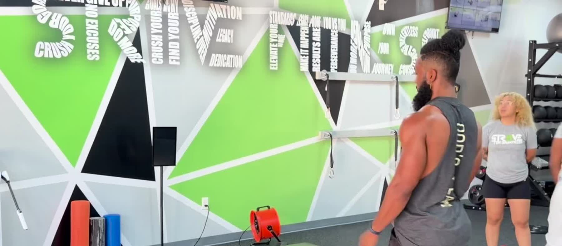 A coach talking a member through the floor at the Strive 11 word wall.