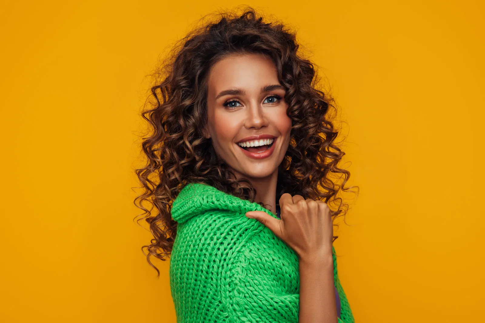 Happy woman with curly hair in a green jumper