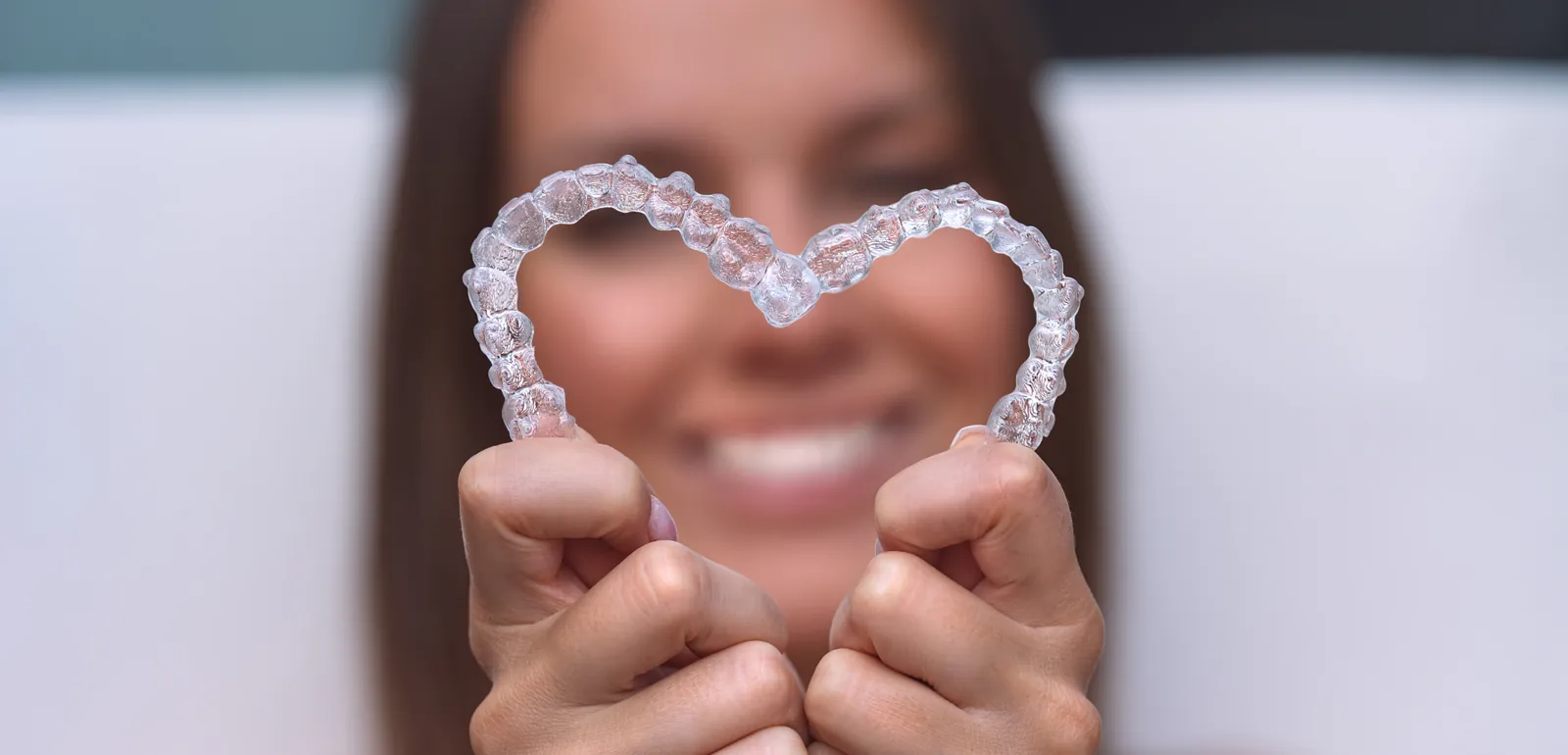 Hands holding clear aligners shaped into a heart, dental treatments in Essex