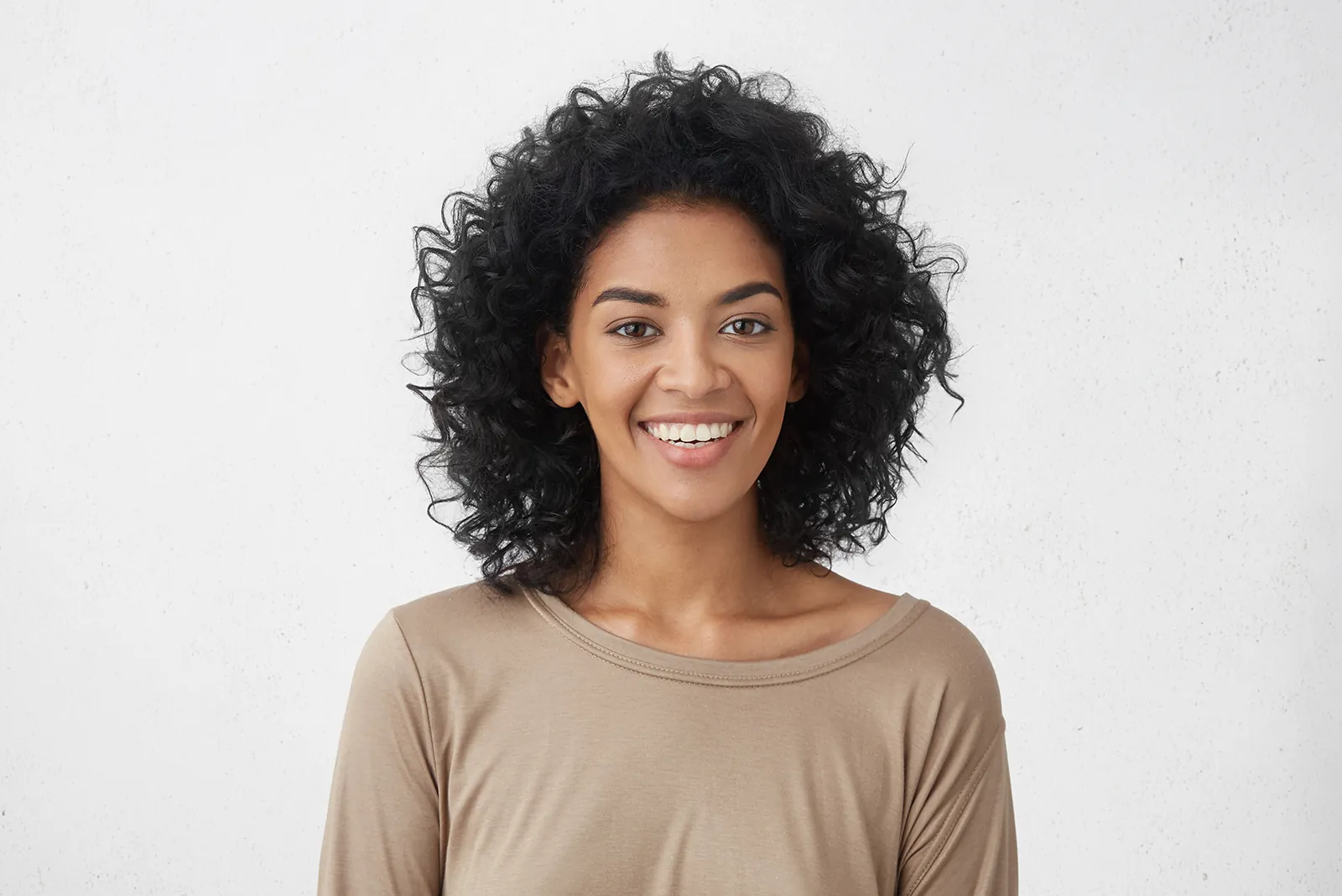 Woman with natural curly hair smiling confidently, Smile and Face dentistry in Chafford Hundred