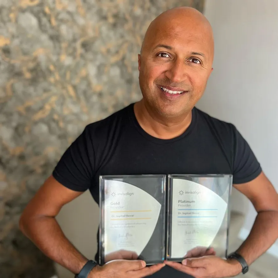 Dr Dave Basrai holding two dental awards