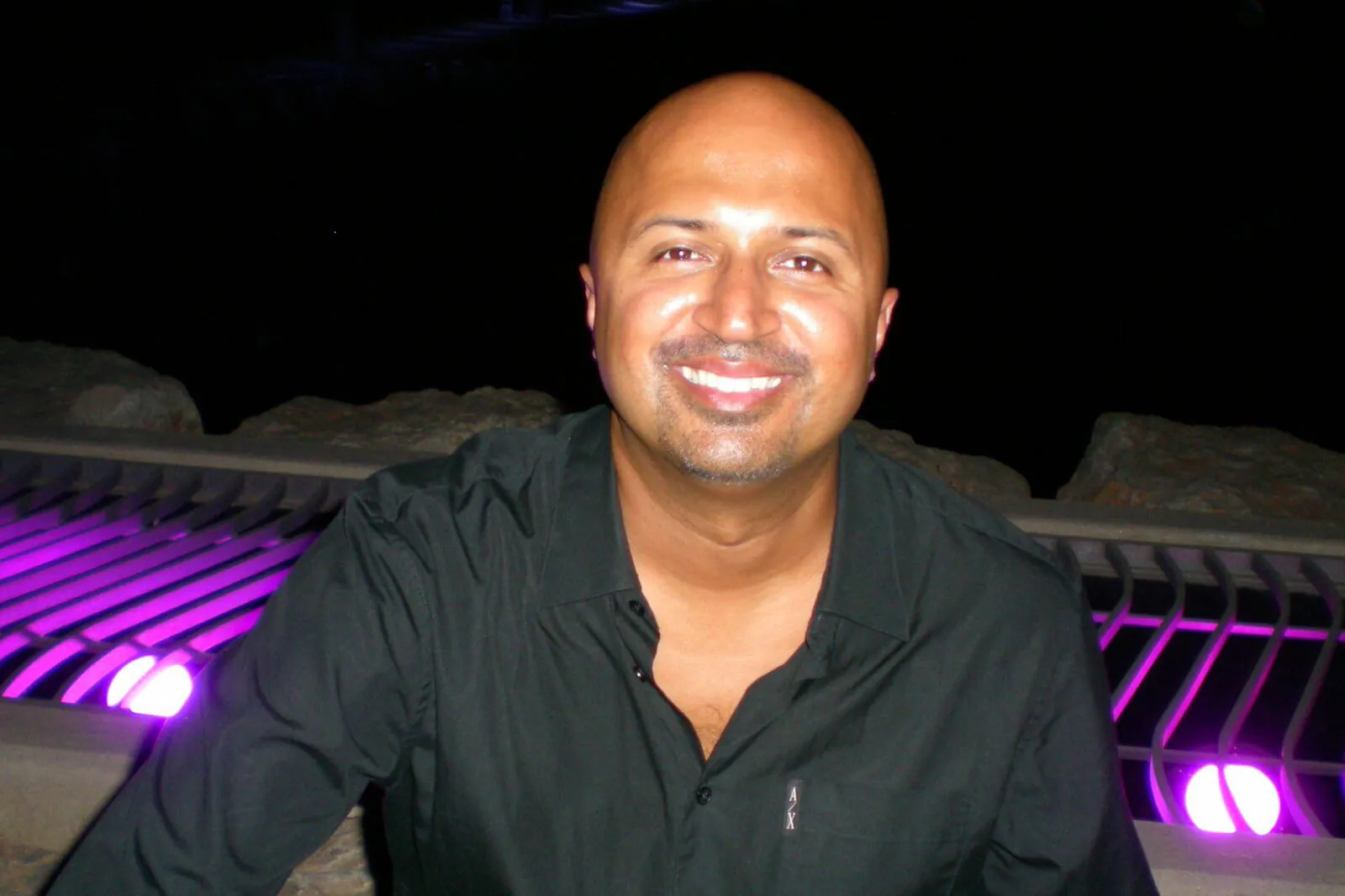 Dr Dave Basrai, dentist in Chafford Hundred, smiling in a black shirt