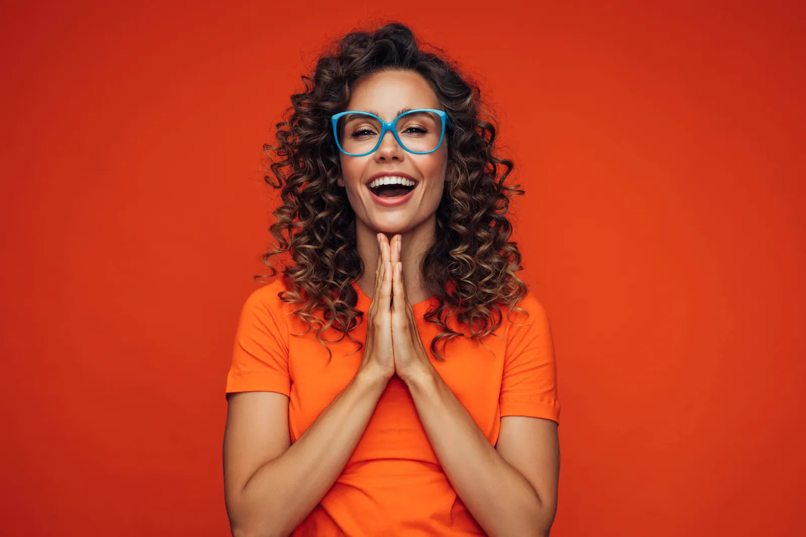 Excited woman in an orange top and blue glasses
