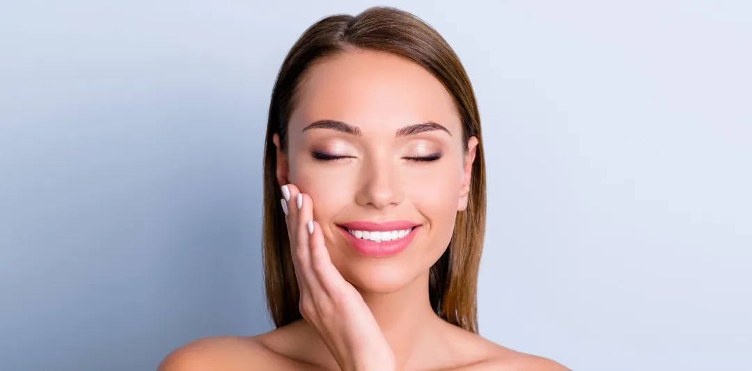 Woman with eyes closed touching her smooth cheek