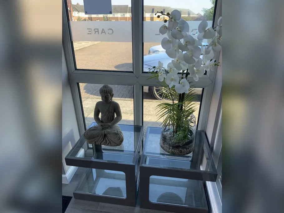 Calm window corner with orchids and a Buddha statue in the practice