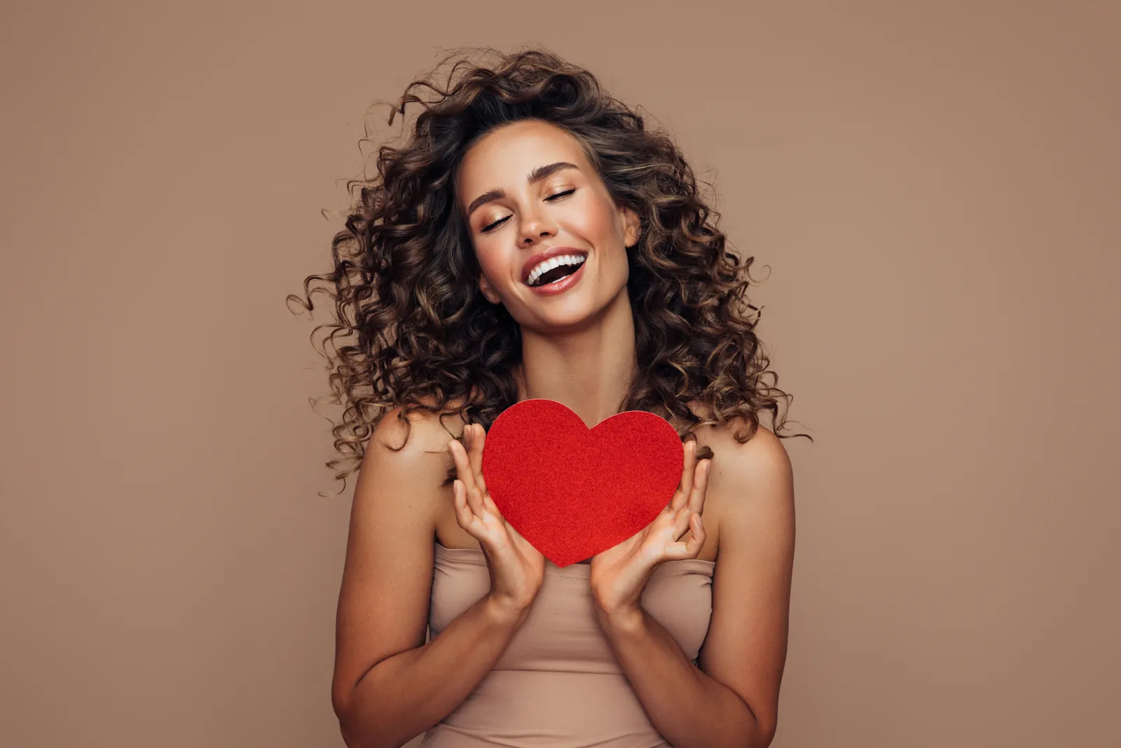 Smiling woman with curly hair holding a red heart